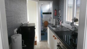 A compact kitchen with a black countertop, stainless steel sink, and a window with blinds. - Inviting 2-bed Chalet in Mablethorpe (Mablethorpe)