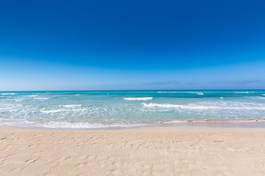 Ein Strand mit klarem, blauem Wasser und sandigem Ufer.