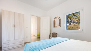A bedroom with a bed, a wardrobe, a chair, and a window with a view of trees. - 3314 Villetta Le Dune Fontanelle by Barbarhouse (Ugento)