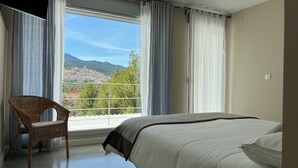 Une chambre à coucher avec un lit, une chaise et une grande fenêtre avec des rideaux.