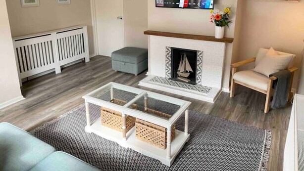 A living room with a fireplace, a television mounted on the wall, and a bookshelf with books.