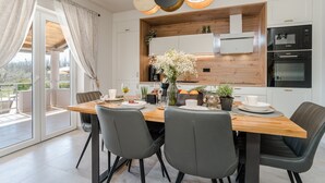 A modern kitchen with a wooden countertop, built-in appliances, and a dining area with a wooden table and chairs. - Villa Paula (Privlaka)