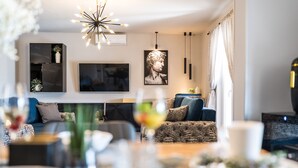A modern living room with a sofa, a dining table with a white cup, and a large painting on the wall. - Villa Paula (Privlaka)