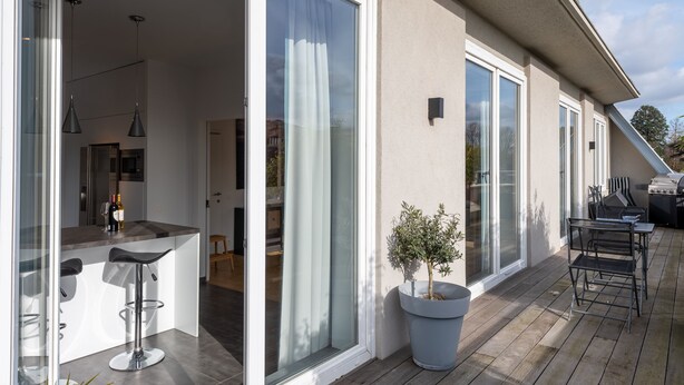 Una cocina moderna con barra, grandes puertas correderas de vidrio y un patio con mobiliario exterior.
