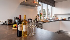 Una cocina moderna con botellas y copas de vino en la encimera, una estufa y un ventanal con vistas.