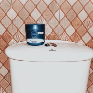 A bathroom with a white toilet and a blue Nivea body cream container on top.