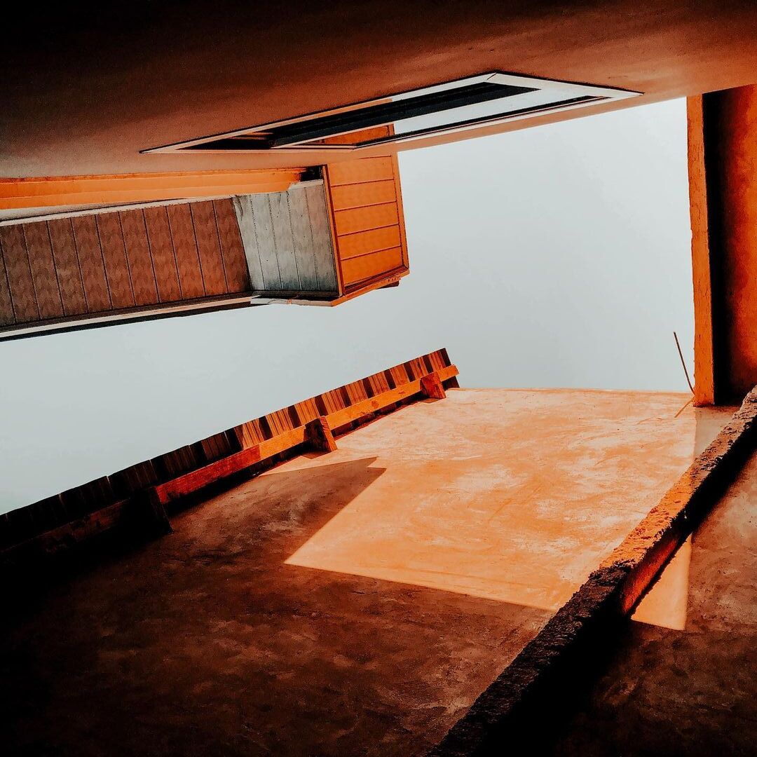 Una habitación con techo inclinado, tragaluz y suelo de madera.