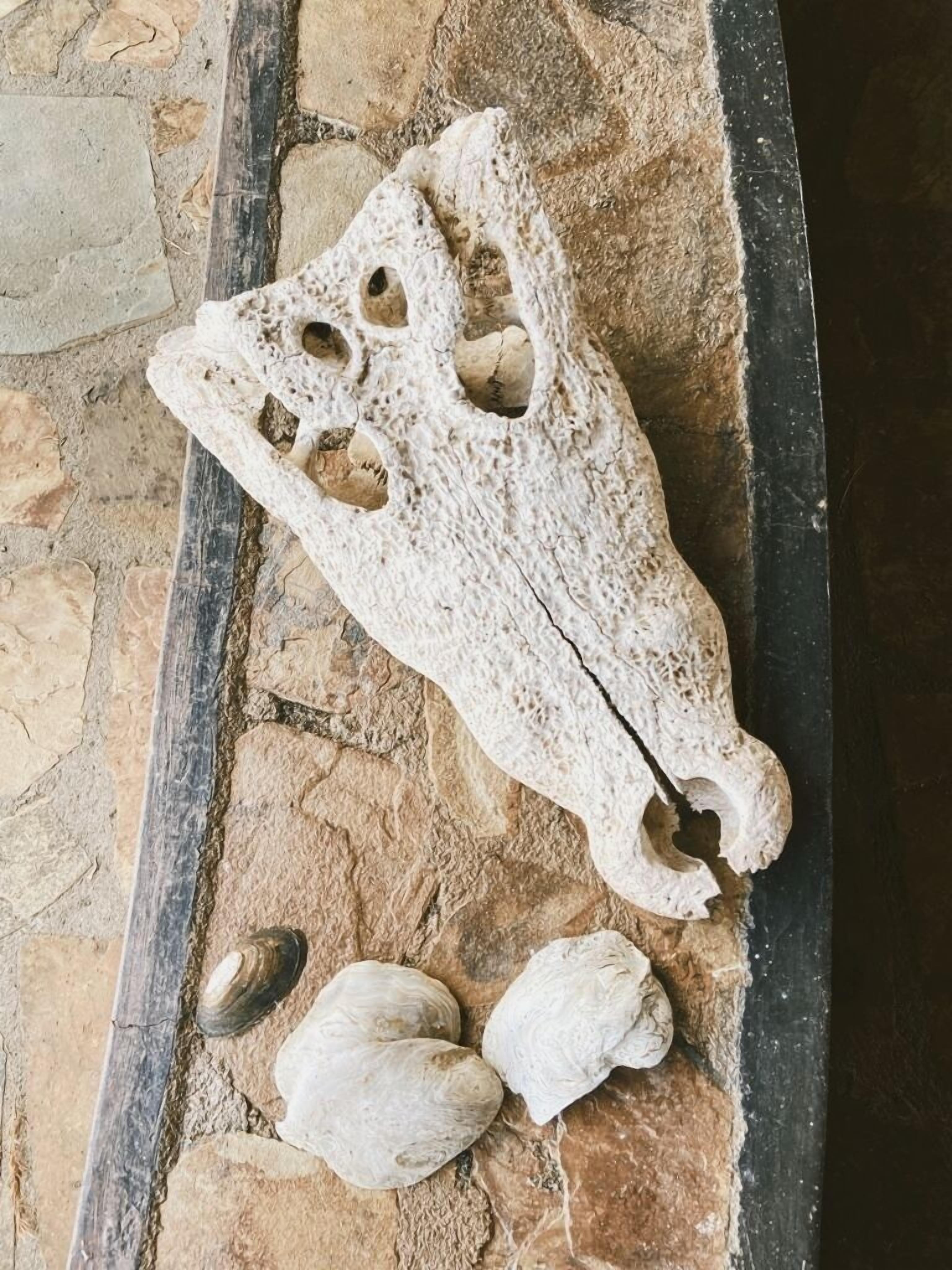 A stone structure with holes, possibly a decorative element, and two smooth stones beside it.