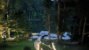 Una scala in pietra con ringhiere in legno conduce a un molo lungo un lago, circondato da alberi e vegetazione.