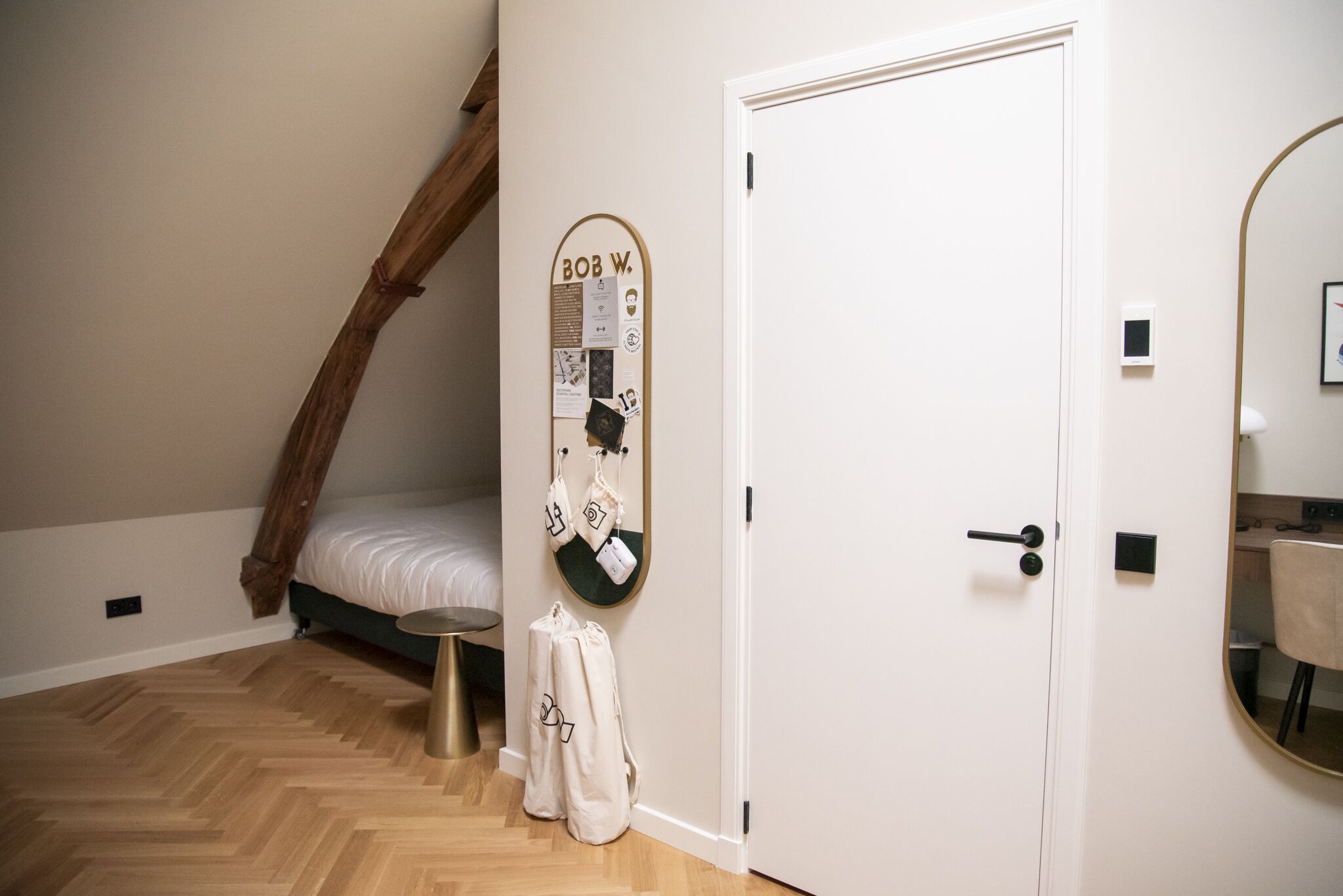 A bedroom with a wooden ceiling, a bed, a wall-mounted bulletin board, and a door.