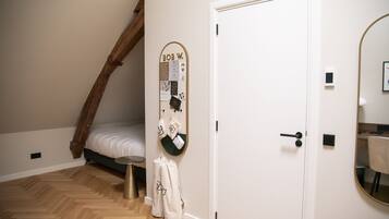A bedroom with a wooden ceiling, a bed, a wall-mounted bulletin board, and a door.