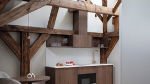 Una cocina moderna con vigas de madera, microondas integrado y encimera blanca.