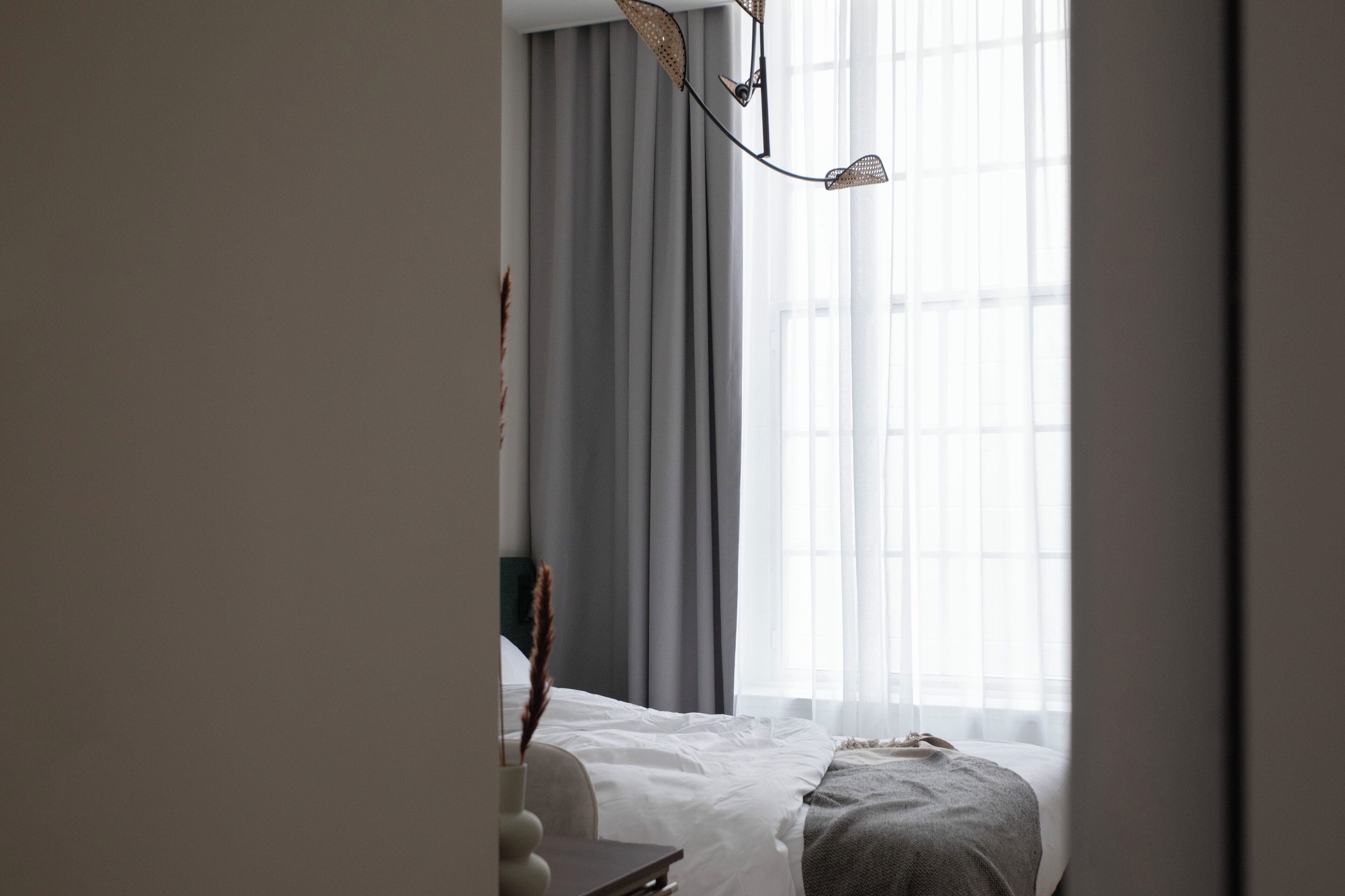 A hotel room with a bed, a desk, and a window with curtains.