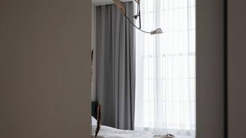 A hotel room with a bed, a desk, and a window with curtains.