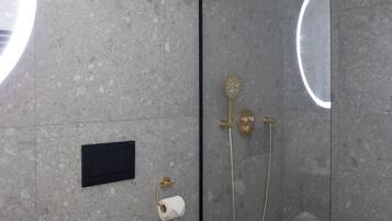 Ett badrum med dusch, en hållare för toalettpapper och en väggmonterad lampa.