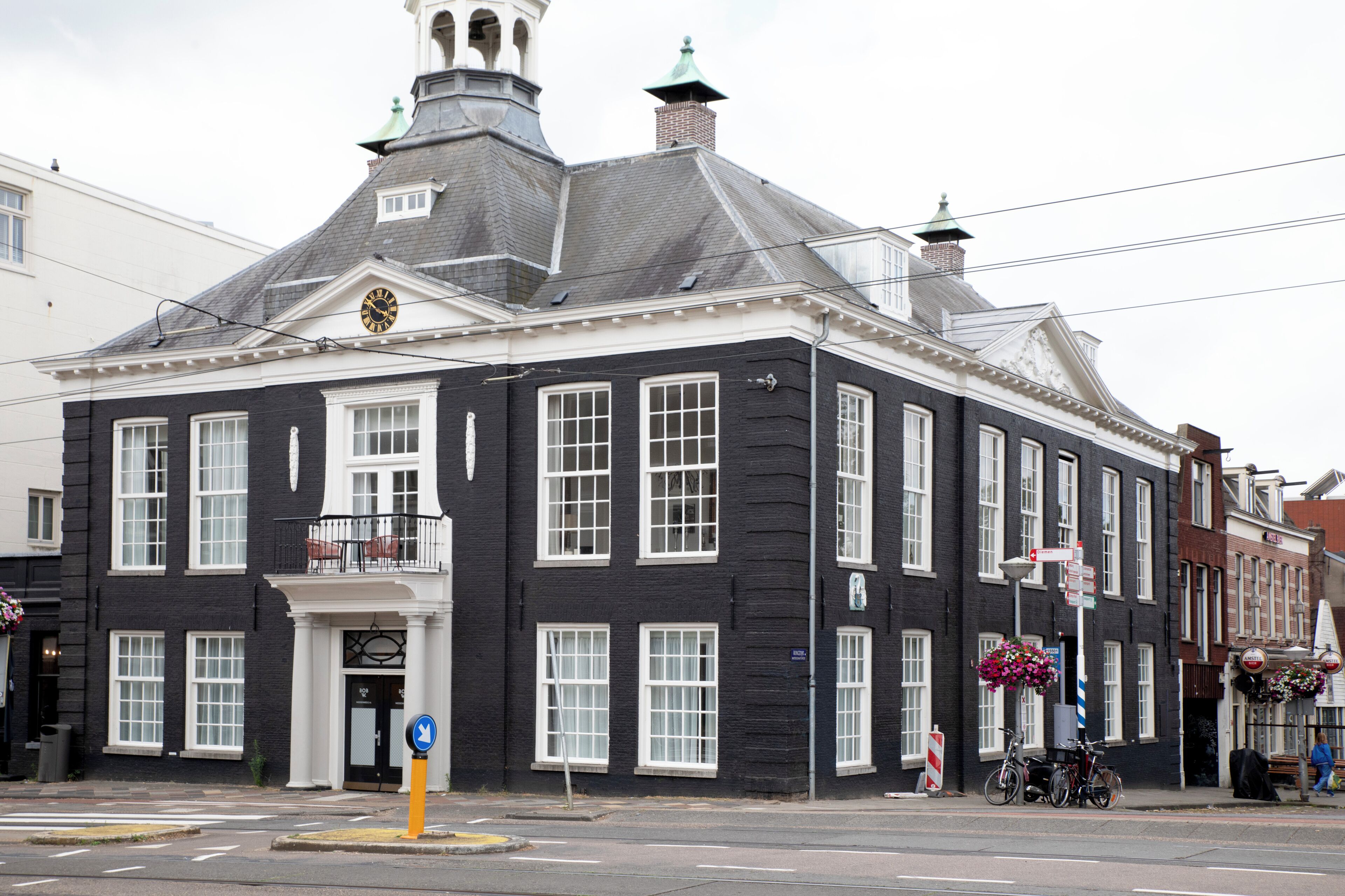 A black and white building with a clock, windows, and a balcony.