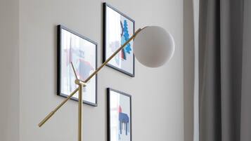 A modern living room with a sofa, a floor lamp, and three framed artworks on the wall.