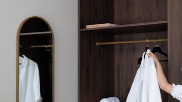 A wardrobe with a mirror, a hanging rod, and a shelf with rolled towels.