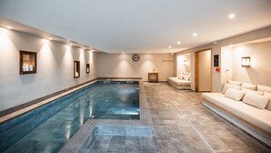 A spa area with a large indoor pool, a sofa, and a small table. - Hotel de la Roche (Beaufort)