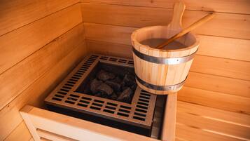 A sauna with a wooden bucket filled with rocks and a wooden ladle.