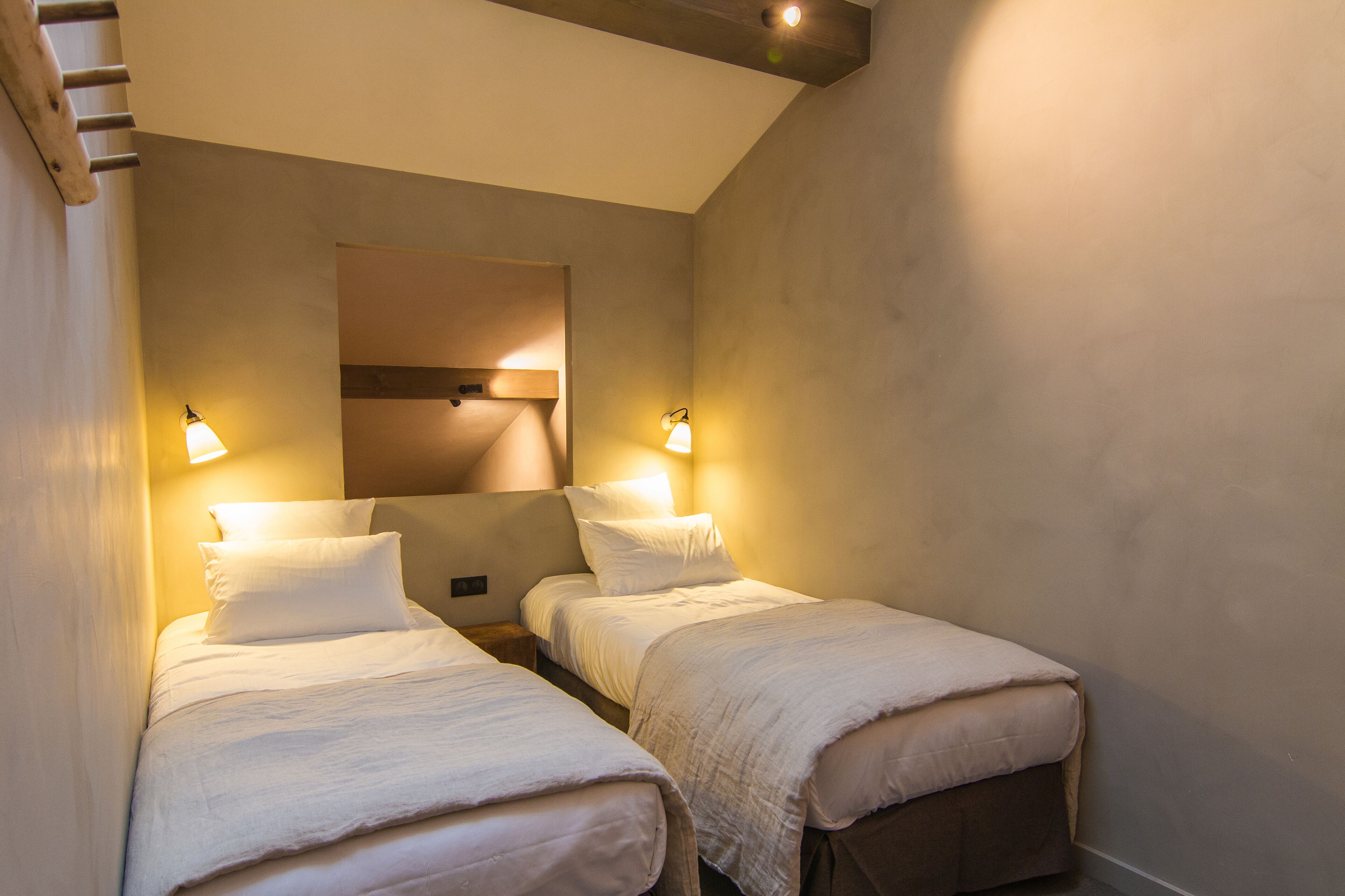 A room with two beds, each with a bedside table and lamp, and a large mirror above the beds.