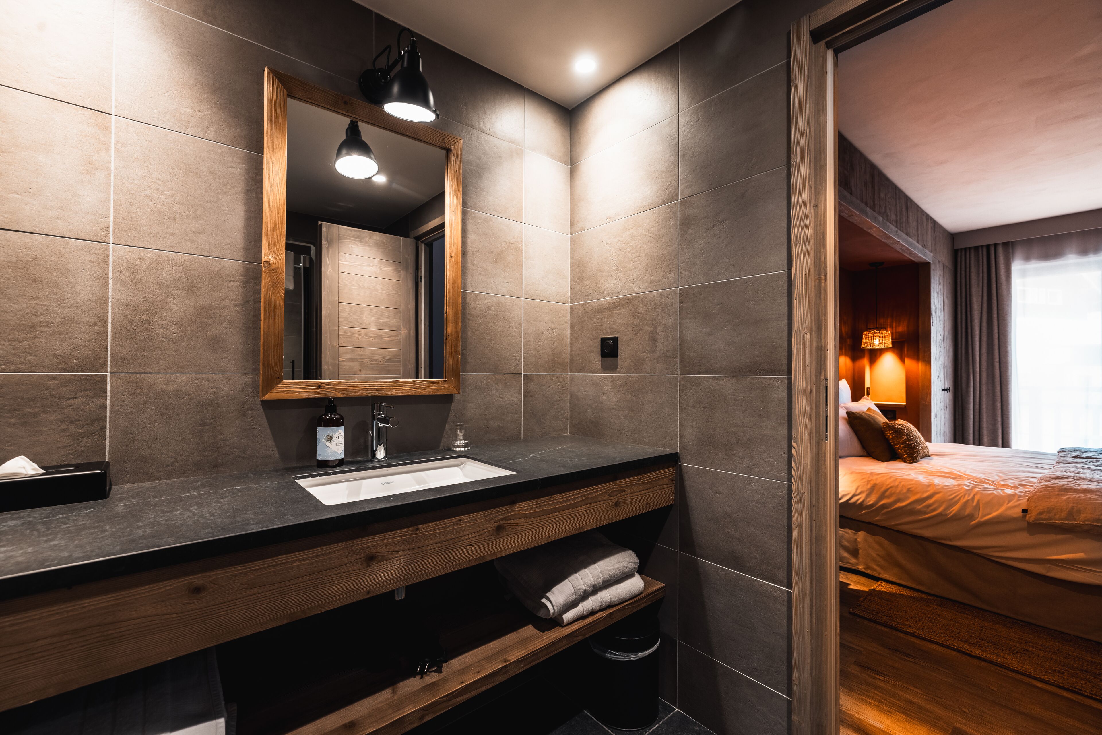 Un baño moderno con tocador de madera, un espejo grande y un lavamanos.
