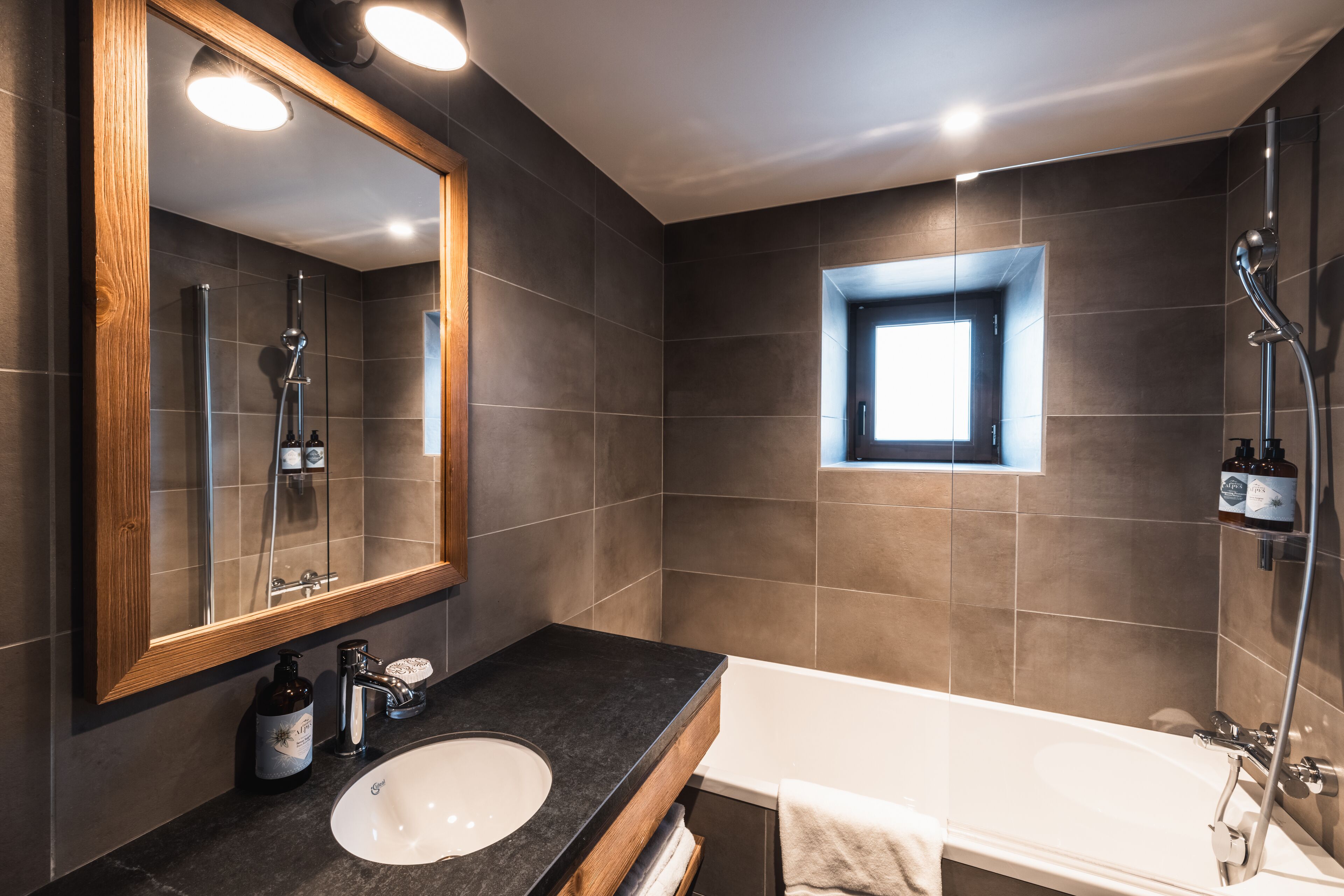 A modern bathroom with a large mirror, a sink, a bathtub, and a shower.