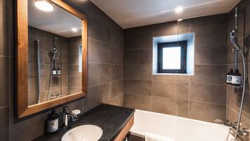 A modern bathroom with a large mirror, a sink, a bathtub, and a shower.