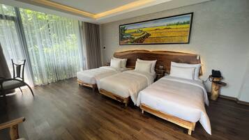 A hotel room with three beds, a dining area, and a large window with curtains.
