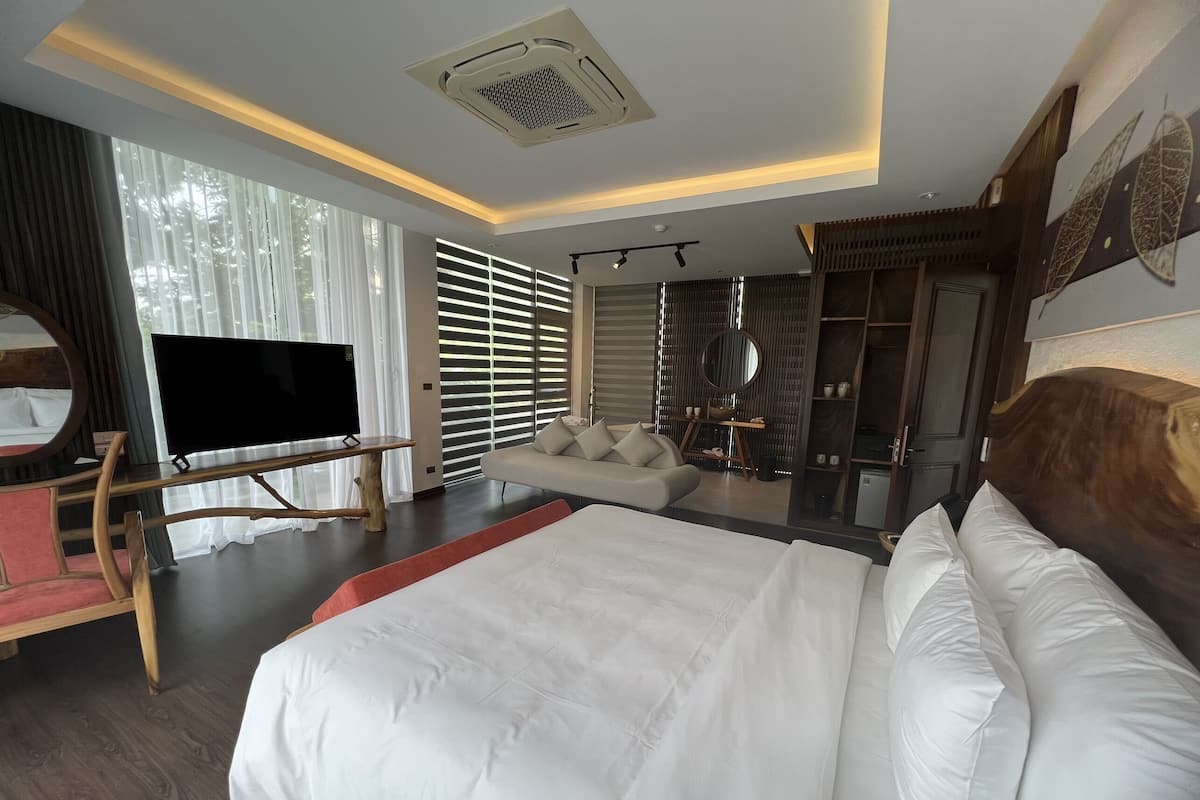 Ein modernes Hotelzimmer mit einem großen Bett, einem Fernseher, einem Sofa und einem Spiegel.