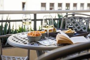 A round metal table with a book, two wine glasses, a bowl of bread, and a tray with bread. - La Musa Apartments & Rooms (Palermo)