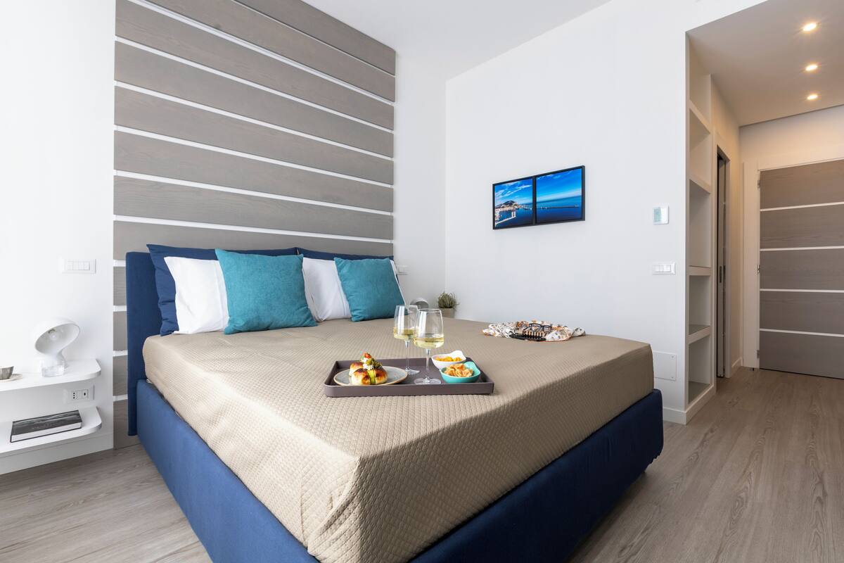 A modern bedroom with a bed, a tray of food, and a painting on the wall.