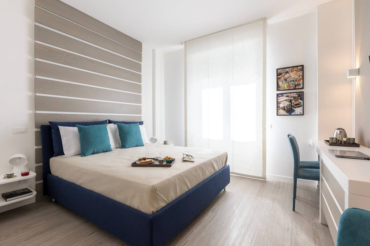 A modern bedroom with a bed, bedside table, and a desk area.