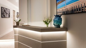 A reception desk with a modern design, a potted plant, and a decorative vase. - La Musa Apartments & Rooms (Palermo)