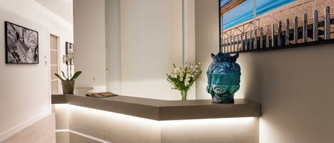 Un mostrador de recepción con diseño moderno, una planta en maceta y un jarrón decorativo.