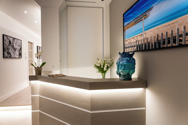 A reception desk with a modern design, a potted plant, and a decorative vase.