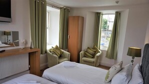 A hotel room with two beds, a wooden wardrobe, a desk with a lamp, and two armchairs. - Rooms at The Angel (Cardigan)