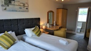 A hotel room with two beds, a desk, a mirror, and a view of the outside. - Rooms at The Angel (Cardigan)