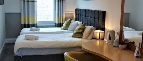 Habitación de hotel con dos camas, un espejo grande, un aparador de madera y una lámpara en el techo.