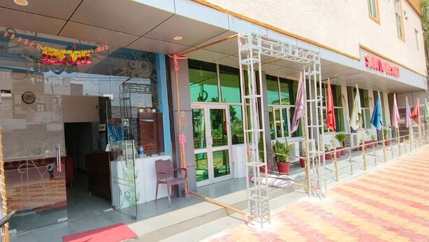 A hotel entrance with a glass facade, outdoor seating, and a covered walkway. - Sanjog Resort (Kota)