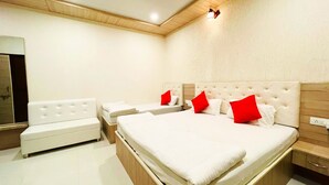 A modern bedroom with a large bed, two bedside tables, a small sofa, and a mirror. - Sanjog Resort (Kota)