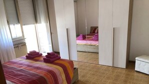 Ein Schlafzimmer mit Bett, Nachttisch, Kleiderschrank und einer kleinen weißen Bank.