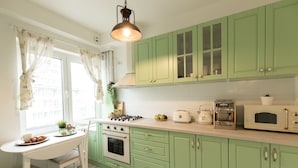 A kitchen with green cabinets, a white countertop, a stove, an oven, a microwave, and a coffee maker. - Metropole Apartments Ateneum Residence (Bucharest)