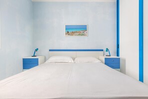 Um quarto com uma cama, duas mesinhas de cabeceira e um quadro na parede.