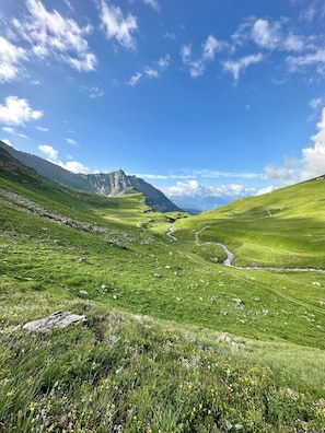 A mountainous landscape with a clear sky, a winding stream, and a small cabin in the distance. - Chalet Violettes (Villaroger)