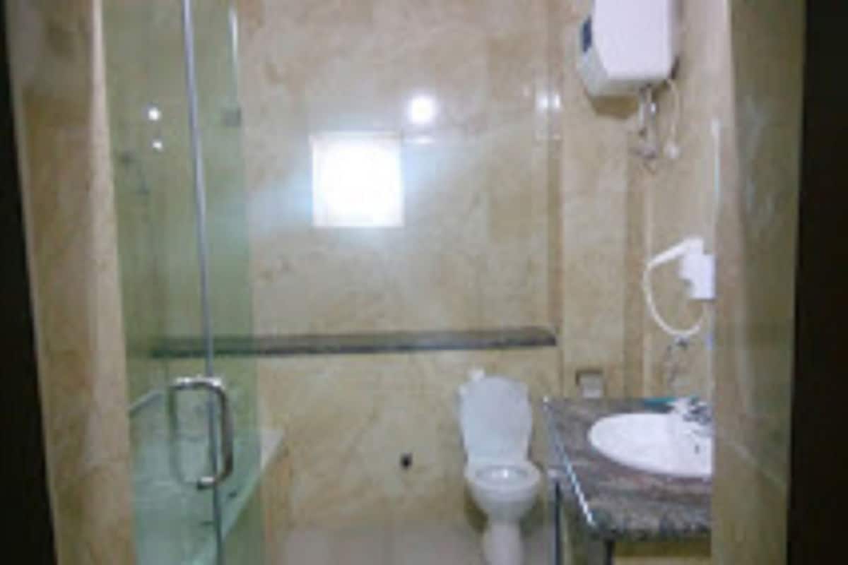 A bathroom with a glass shower enclosure, a toilet, and a sink with a marble countertop.
