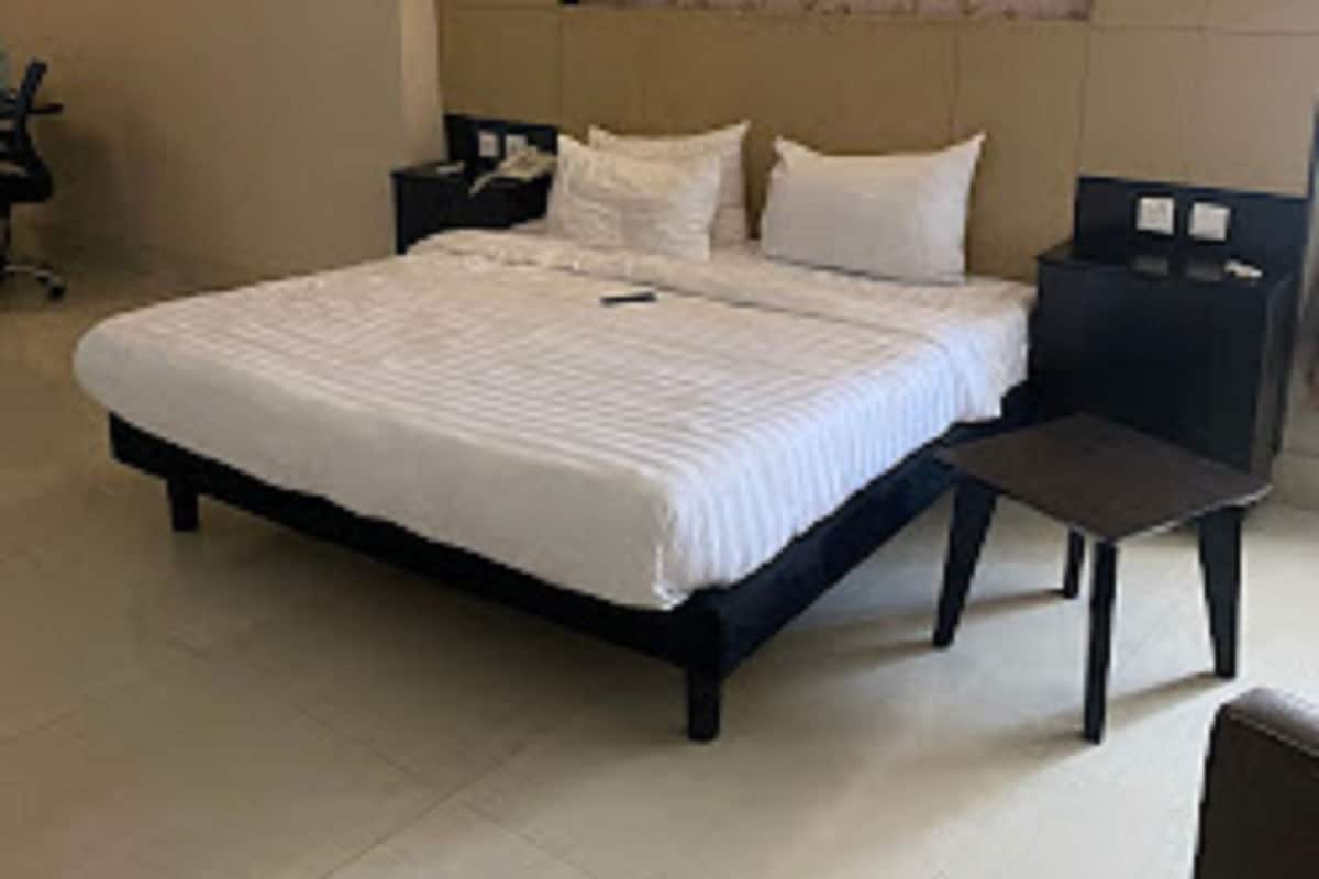 A bedroom with a bed, bedside tables, a chair, and a wall-mounted light fixture.