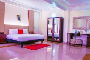 Una habitación de hotel con una cama, un tapete rojo, un espejo y una mesita.
