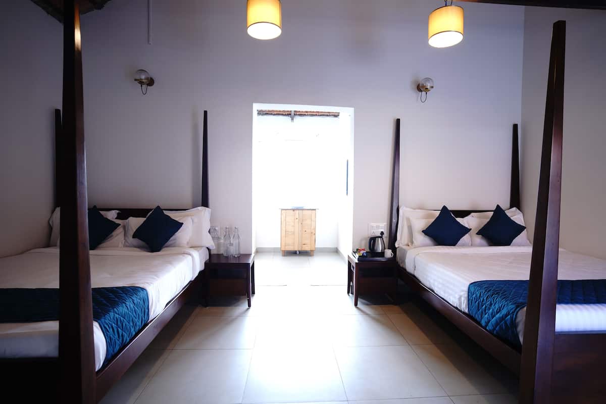 A hotel room with two beds, a wooden wardrobe, and a view of the outside.