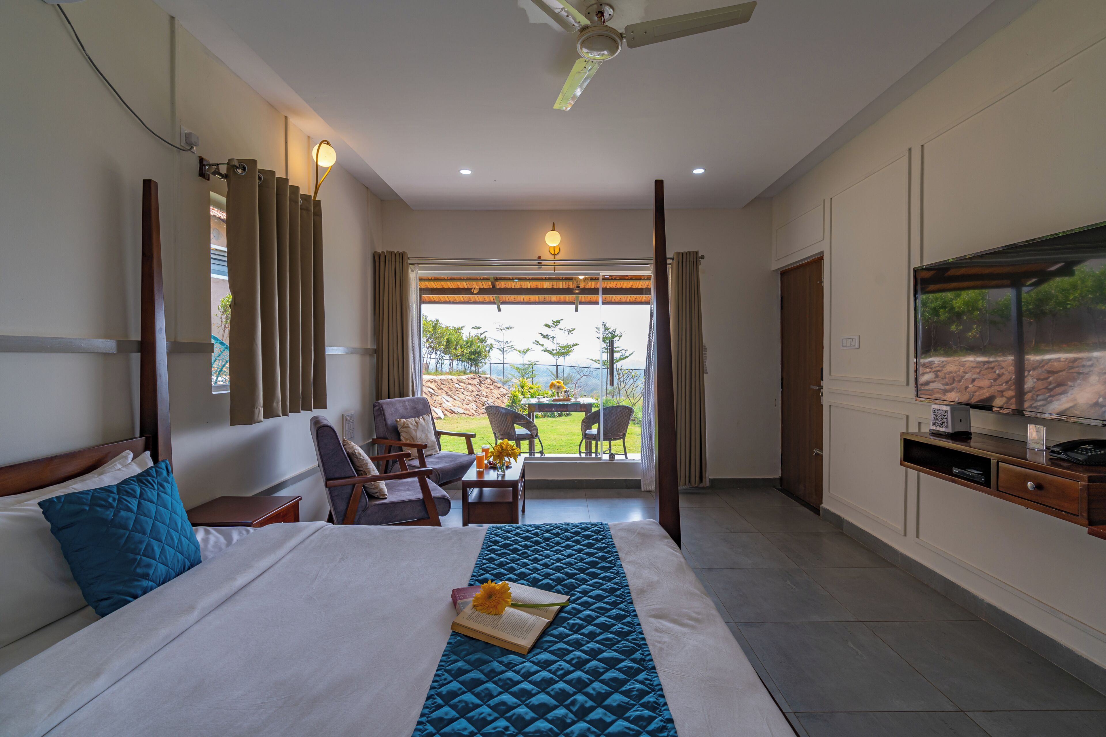Habitación de hotel con cama, escritorio, silla, televisor y vistas al exterior.